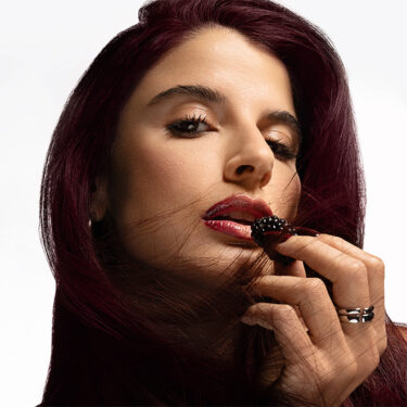 Woman with PRAVANA 6RV Red Violet Dark Blonde Hair Color Eating Fruit